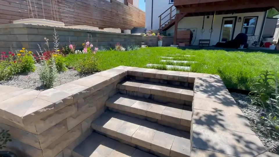 Block retaining wall steps rising to a lawn with stepping pads