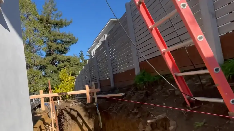 Side yard excavated with forms set for a concrete retaining wall